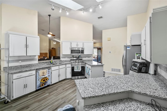 50 Florida Park Dr, Palm Coast, FL 32137 - kitchen with stainless steel appliances, a skylight, a peninsula, rail lighting, and white cabinets