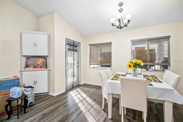 dining space featuring dark hardwood / wood-style flooring, lofted ceiling, and a notable chandelier