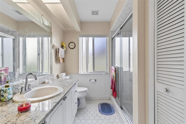 bathroom featuring walk in shower, plenty of natural light, vanity, and toilet