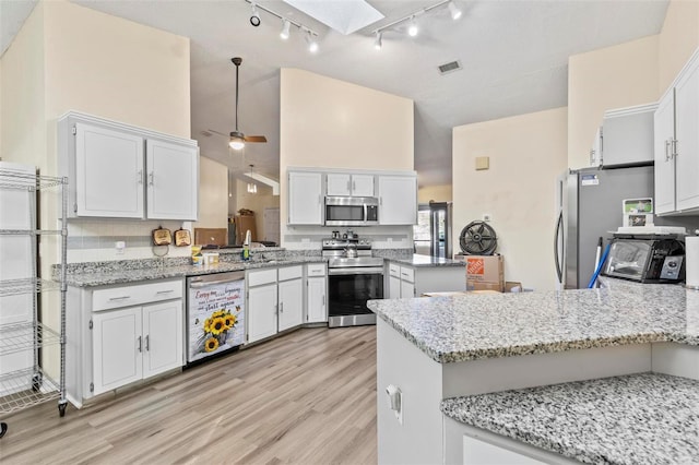 kitchen with kitchen peninsula, white cabinetry, a skylight, and appliances with stainless steel finishes