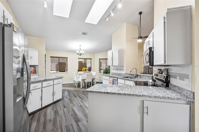 50 Florida Park Dr, Palm Coast, FL 32137 - kitchen with stainless steel appliances, a peninsula, wood finished floors, and white cabinets