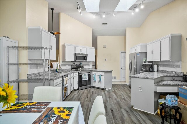 50 Florida Park Dr, Palm Coast, FL 32137 - kitchen featuring stainless steel appliances, high vaulted ceiling, rail lighting, a skylight, and white cabinetry