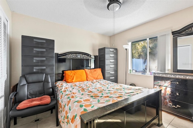 bedroom with ceiling fan, light tile patterned floors, and a textured ceiling