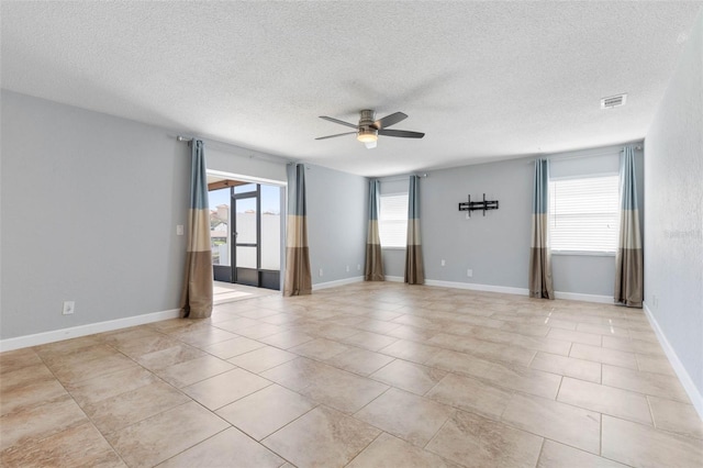 empty room featuring a textured ceiling, light tile patterned floors, and ceiling fan