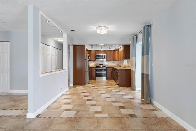 kitchen with stainless steel appliances, a textured ceiling, sink, and rail lighting