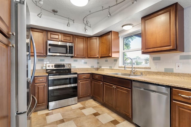 kitchen featuring stainless steel appliances, sink, rail lighting, a textured ceiling, and backsplash