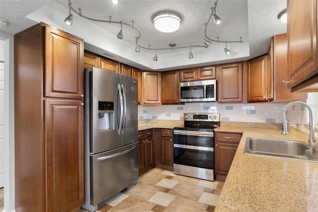 kitchen with light stone counters, decorative backsplash, a textured ceiling, sink, and appliances with stainless steel finishes