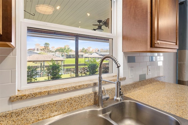 details featuring decorative backsplash, sink, and light stone countertops