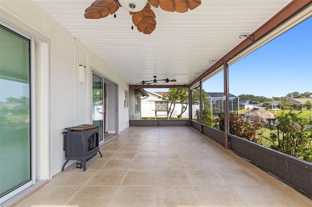 sunroom / solarium featuring a wood stove and ceiling fan