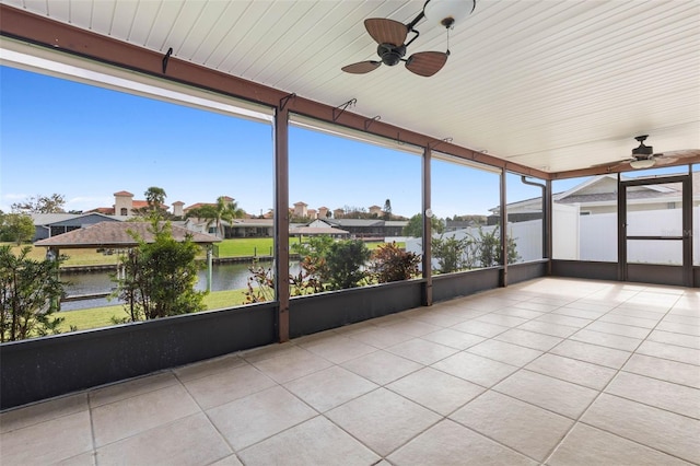 unfurnished sunroom featuring ceiling fan and a water view