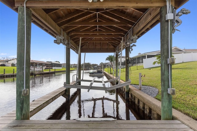 view of dock with a lawn and a water view