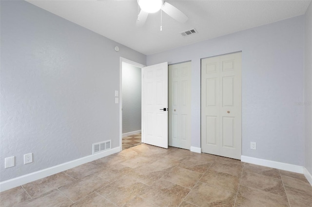 unfurnished bedroom with multiple closets and ceiling fan