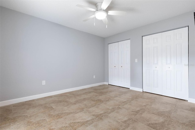 unfurnished bedroom featuring ceiling fan and two closets