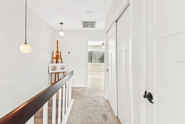 corridor featuring light carpet and a textured ceiling