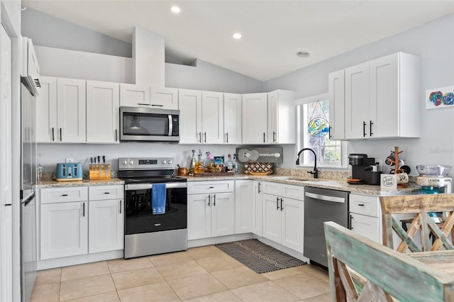 kitchen featuring vaulted ceiling, white cabinetry, sink, and appliances with stainless steel finishes