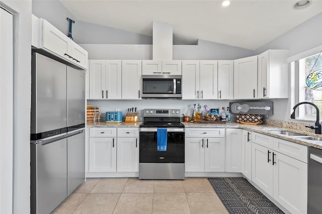 kitchen featuring lofted ceiling, light stone counters, white cabinets, sink, and appliances with stainless steel finishes