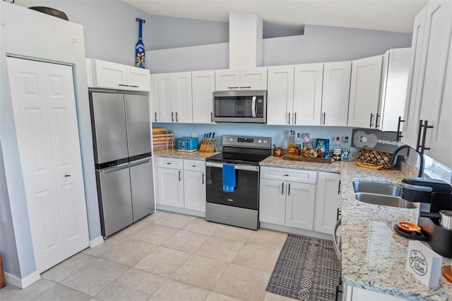 kitchen featuring stainless steel appliances, white cabinets, sink, and vaulted ceiling