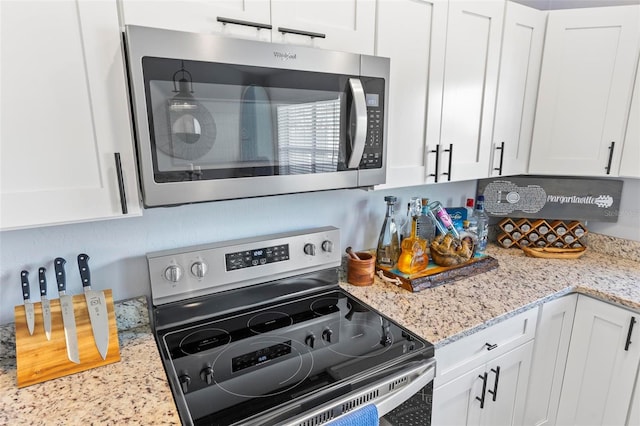 kitchen featuring stainless steel appliances, light stone countertops, and white cabinetry