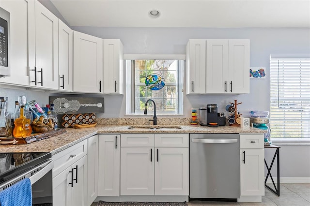 kitchen featuring stainless steel appliances, white cabinetry, sink, and light stone counters