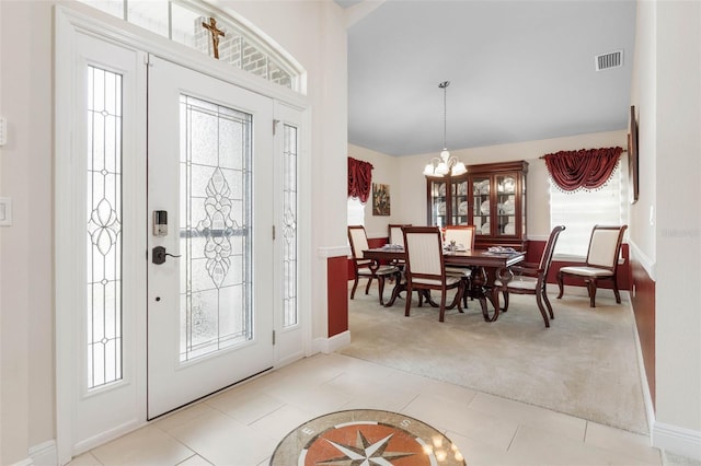 entryway with light colored carpet, a healthy amount of sunlight, and an inviting chandelier