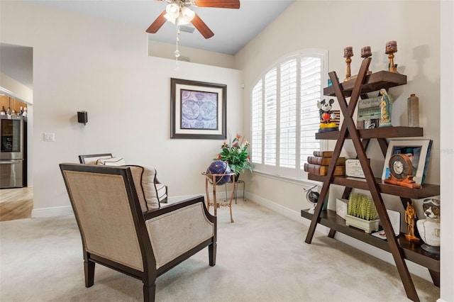 living area featuring light colored carpet and ceiling fan