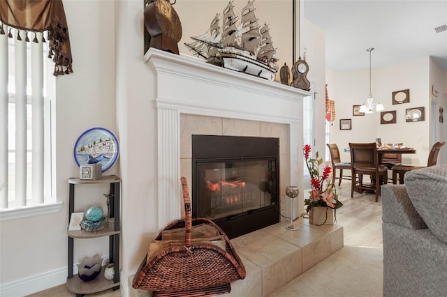 living room with a tiled fireplace, light carpet, and a notable chandelier