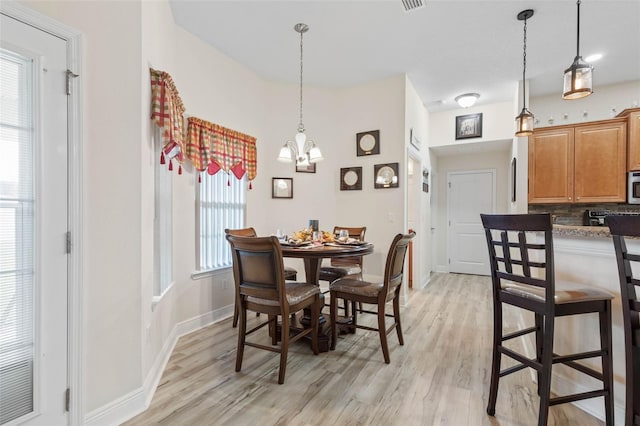 dining room featuring light wood-type flooring, a wealth of natural light, and a notable chandelier