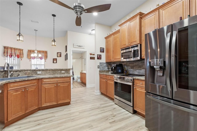 kitchen with stainless steel appliances, sink, stone counters, light hardwood / wood-style flooring, and pendant lighting