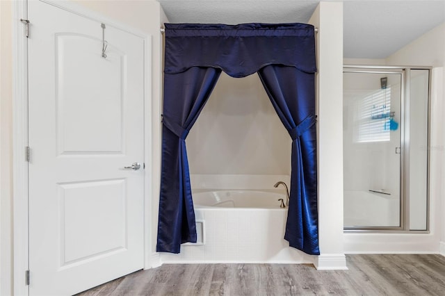 bathroom with shower with separate bathtub, a textured ceiling, and hardwood / wood-style flooring