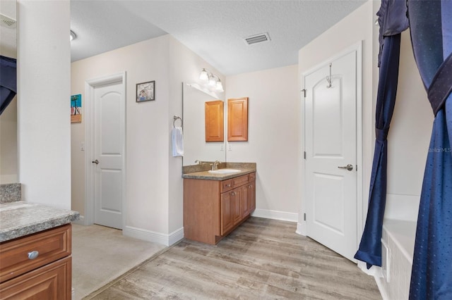 bathroom with hardwood / wood-style floors, a textured ceiling, and vanity