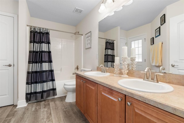 full bathroom with vanity, toilet, a textured ceiling, hardwood / wood-style floors, and shower / tub combo with curtain