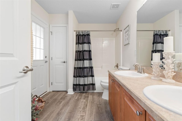 full bathroom featuring vanity, a textured ceiling, shower / tub combo, hardwood / wood-style floors, and toilet