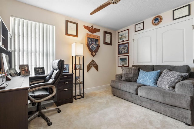 office space with a textured ceiling, light colored carpet, and ceiling fan