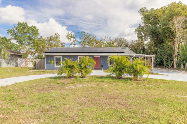 ranch-style house with a front lawn, solar panels, and a carport