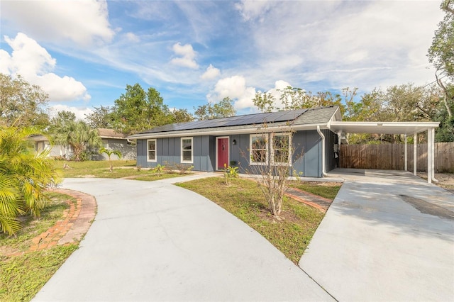 single story home featuring solar panels, a front yard, and a carport