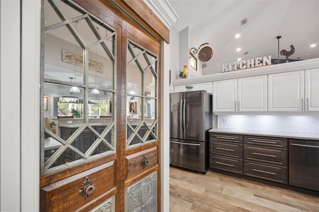 kitchen featuring freestanding refrigerator, white cabinetry, and decorative backsplash