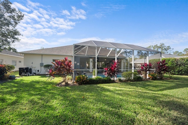 back of house with a lanai, a lawn, and stucco siding