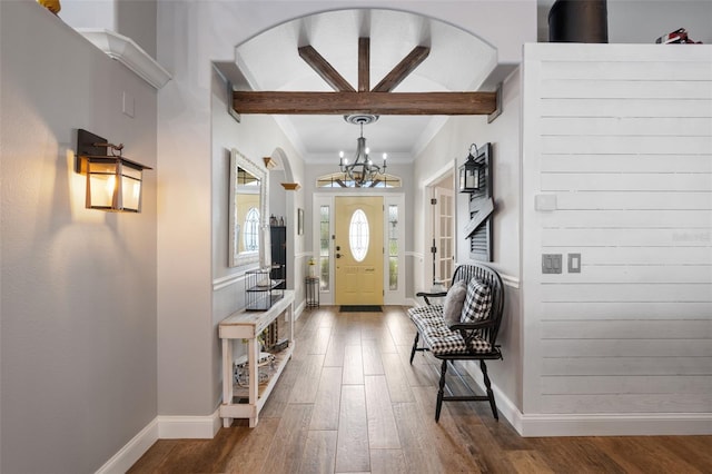 foyer entrance featuring baseboards, ornamental molding, wood finished floors, a chandelier, and beam ceiling