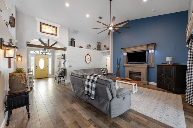 living area featuring high vaulted ceiling, a glass covered fireplace, dark wood-style flooring, and visible vents