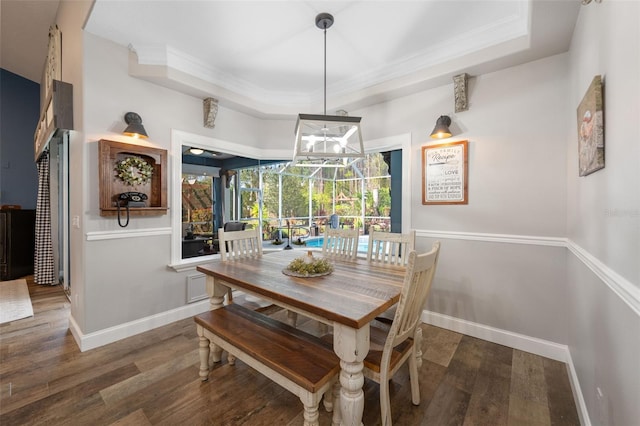 dining room with baseboards, a tray ceiling, wood finished floors, and ornamental molding