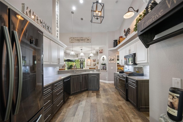 kitchen with stainless steel appliances, a peninsula, a sink, white cabinets, and backsplash