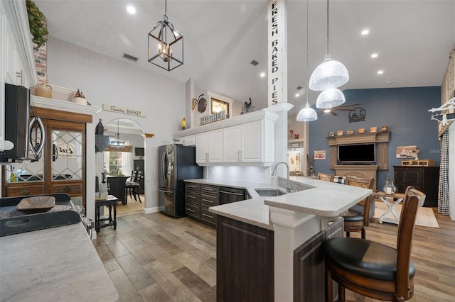 kitchen featuring visible vents, arched walkways, light wood-style flooring, freestanding refrigerator, and a sink