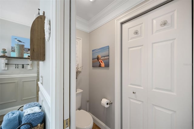 bathroom featuring a decorative wall, toilet, and crown molding