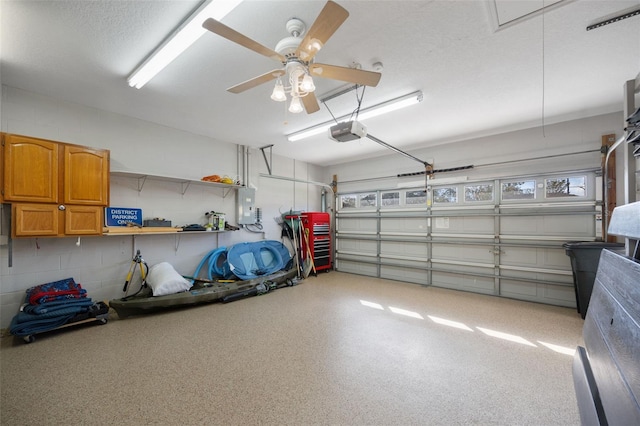 garage featuring concrete block wall, ceiling fan, electric panel, and a garage door opener