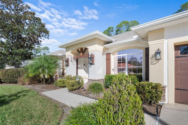 entrance to property with a shingled roof and stucco siding