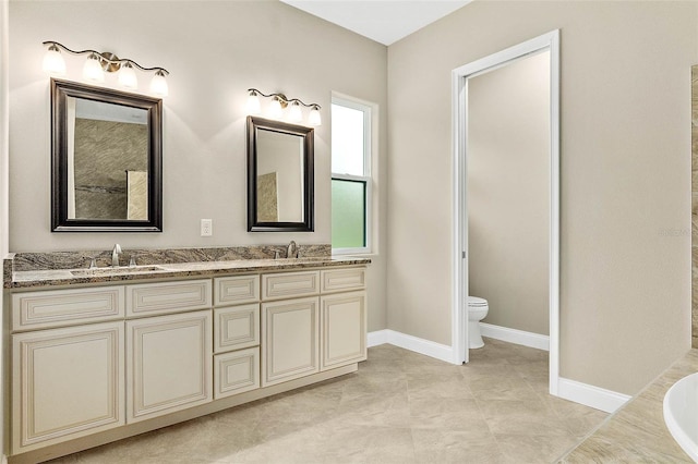 bathroom featuring tile patterned flooring, a bathtub, vanity, and toilet