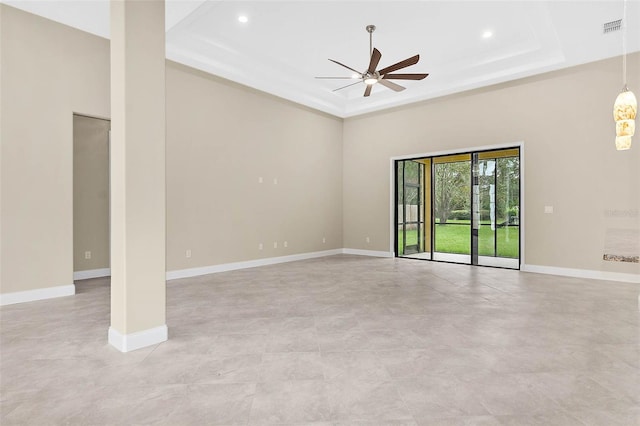 unfurnished room with ceiling fan and a tray ceiling