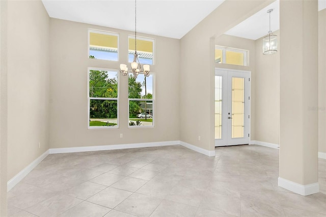 interior space with an inviting chandelier, french doors, light tile patterned floors, and a towering ceiling