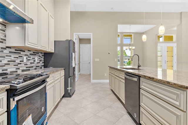 kitchen featuring tasteful backsplash, light stone counters, stainless steel appliances, extractor fan, and sink