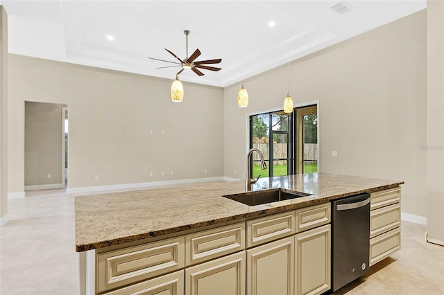 kitchen with an island with sink, light stone countertops, sink, and a tray ceiling